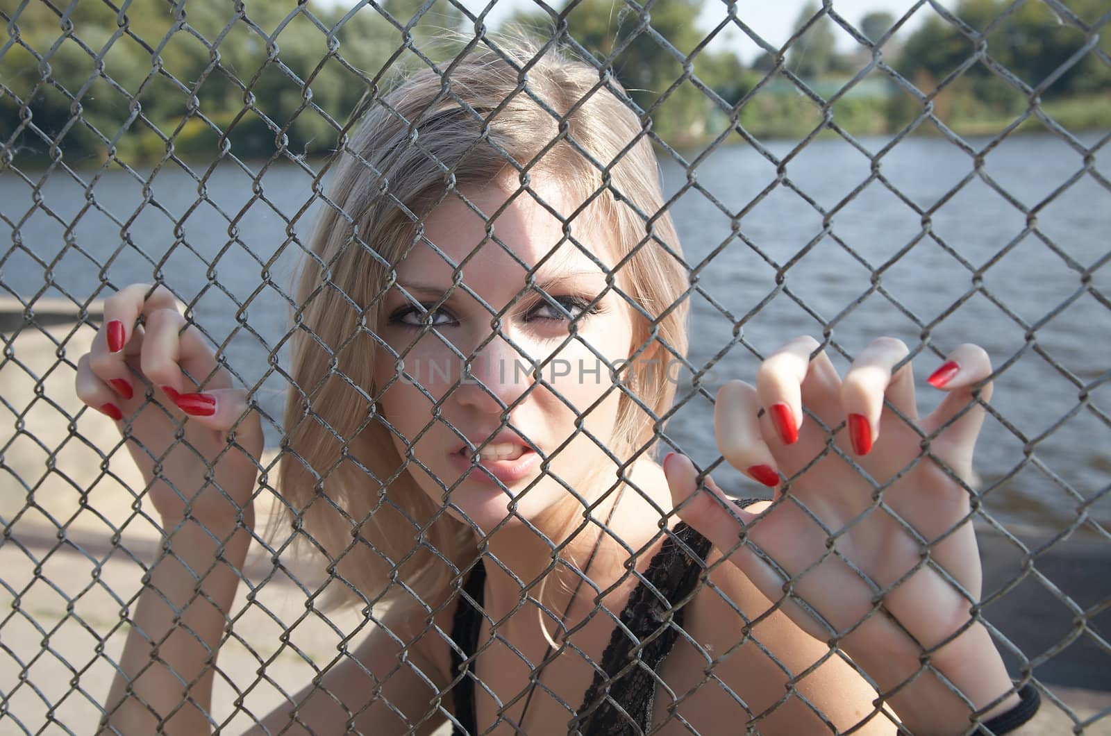 The girl has spitefully seized hands an iron grid