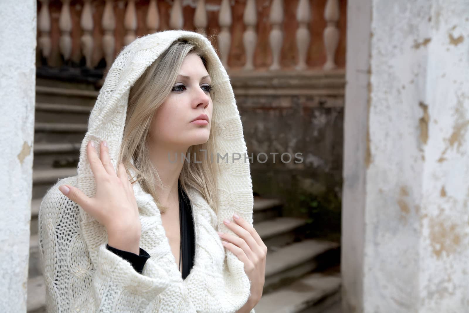 The thoughtful girl in  knitted dress on  background of a wall
