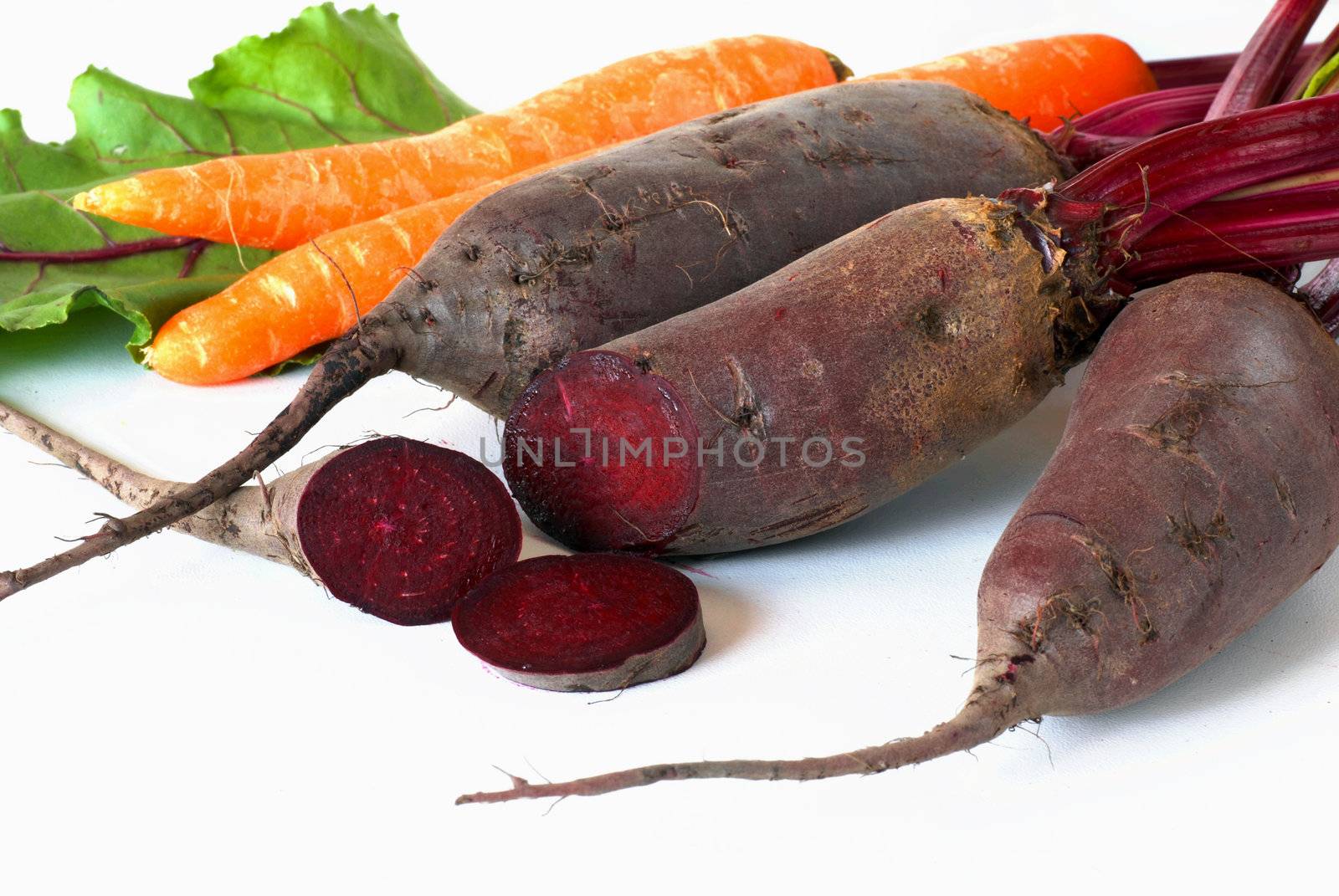 bunch of raw beet and carrot roots over white background