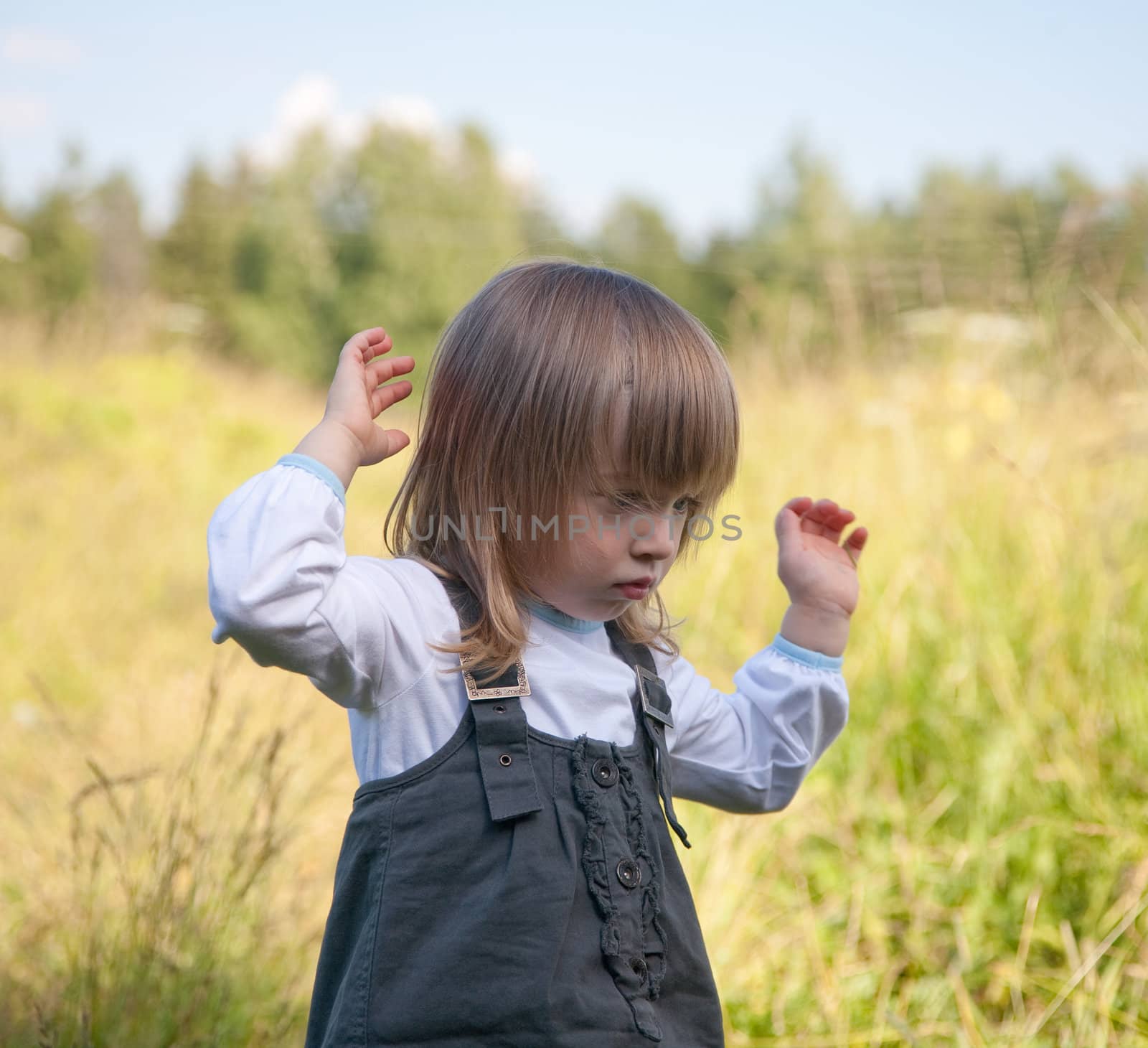 The little girl on summer meadow stretches a hand