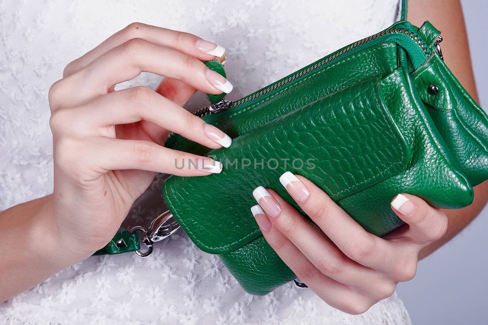 Beautiful female hands with manicure hold an open green handbag