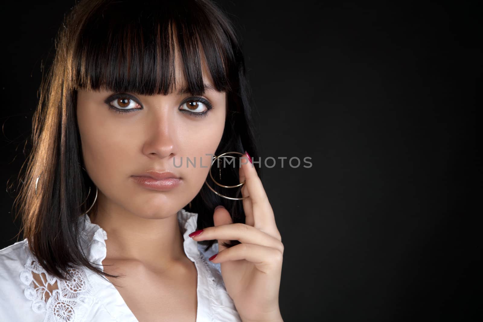 The girl holds  hand an earring on a black background
