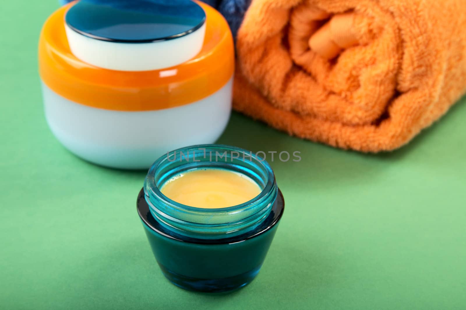 Cosmetic cream and towels on a green background