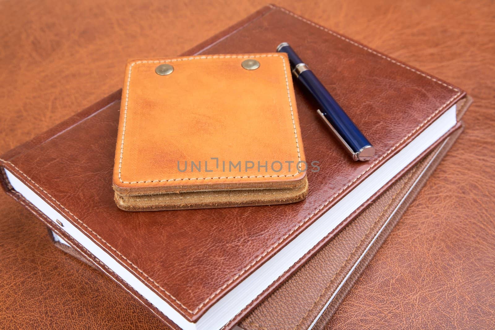 Leather organizers and fountain pen on a textural background