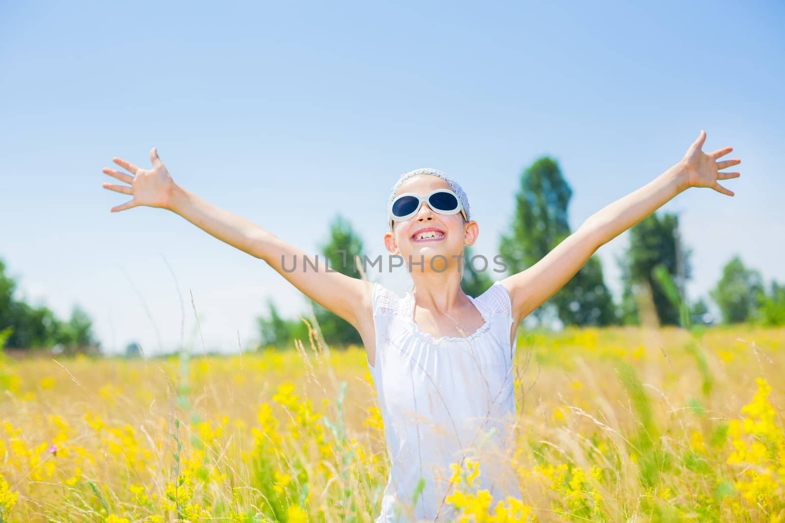 Adorable happy girl in glasses in flowers yellow field. Summer freedom andjoy concept.