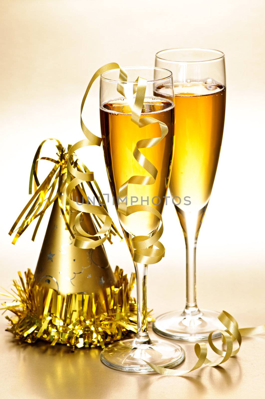 Two full champagne flutes with party hat and ribbons