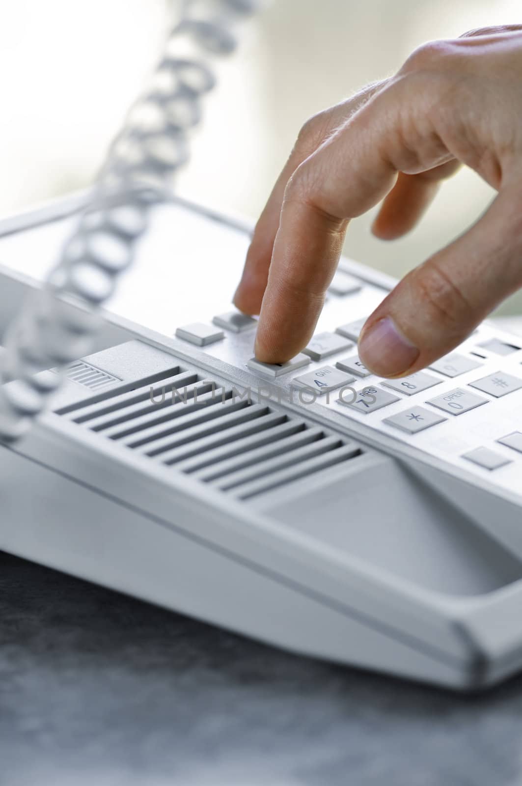 Close up of fingers dialing a desktop telephone