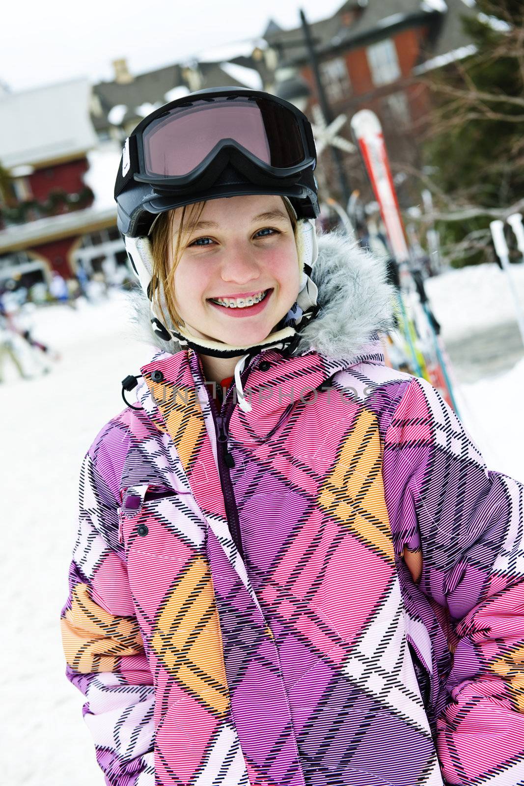 Portrait of happy teenage girl in ski helmet and goggles at winter resort