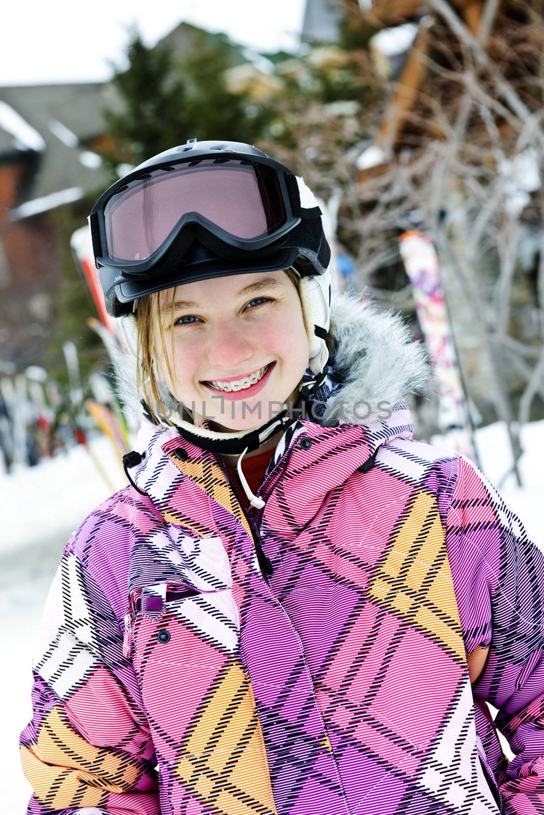 Portrait of happy teenage girl in ski helmet and goggles at winter resort