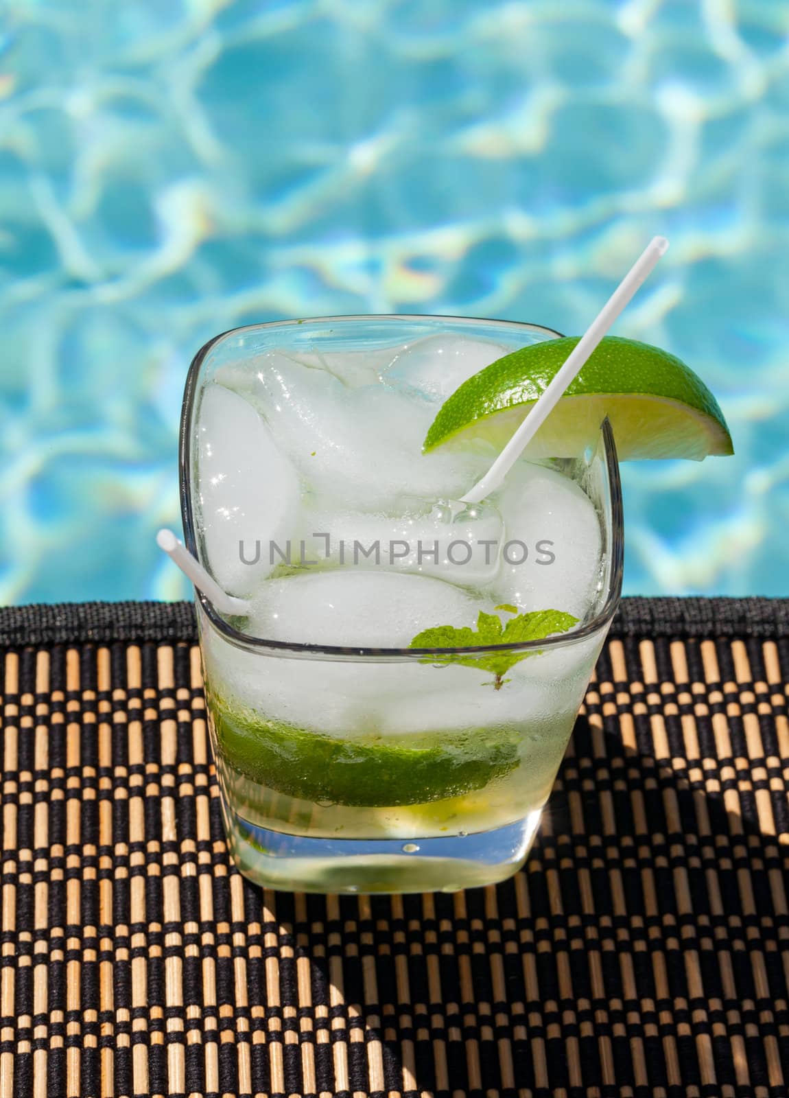 Glass of ice cold majito in glass by side of swimming pool