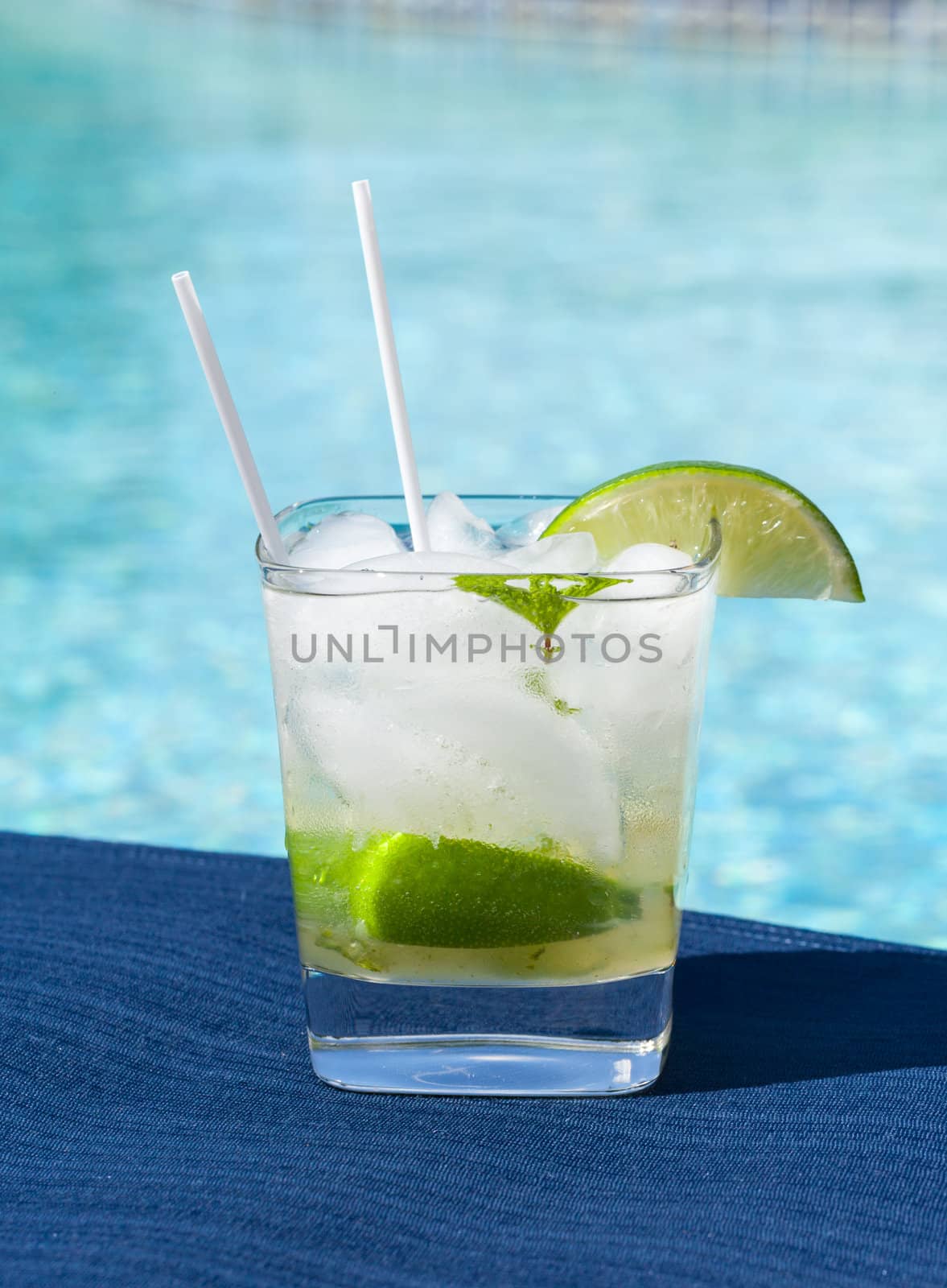 Glass of ice cold majito in glass by side of swimming pool