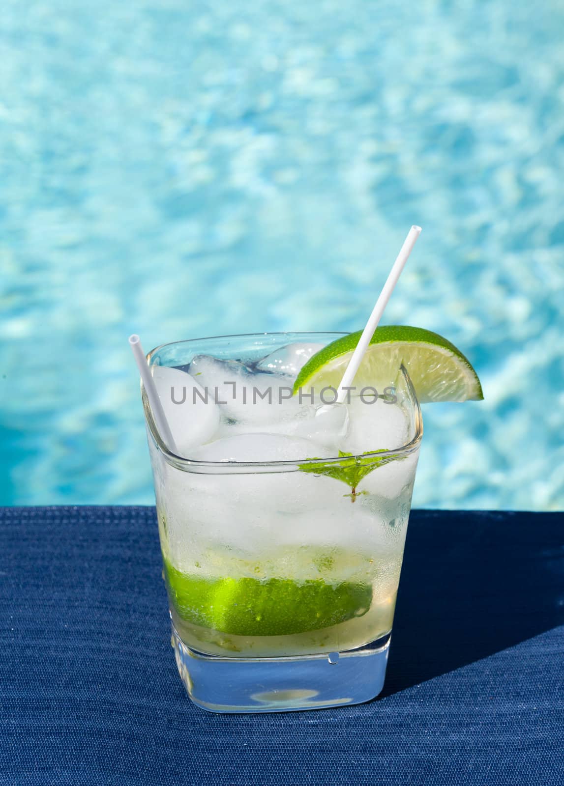 Glass of ice cold majito in glass by side of swimming pool
