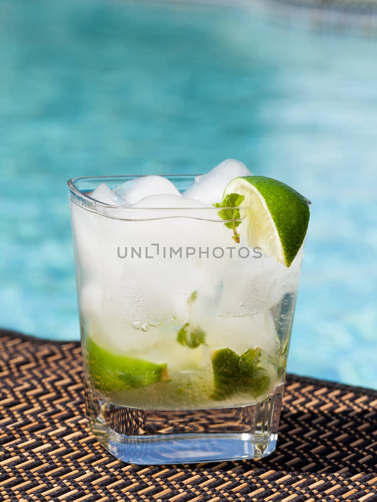 Glass of ice cold majito in glass by side of swimming pool