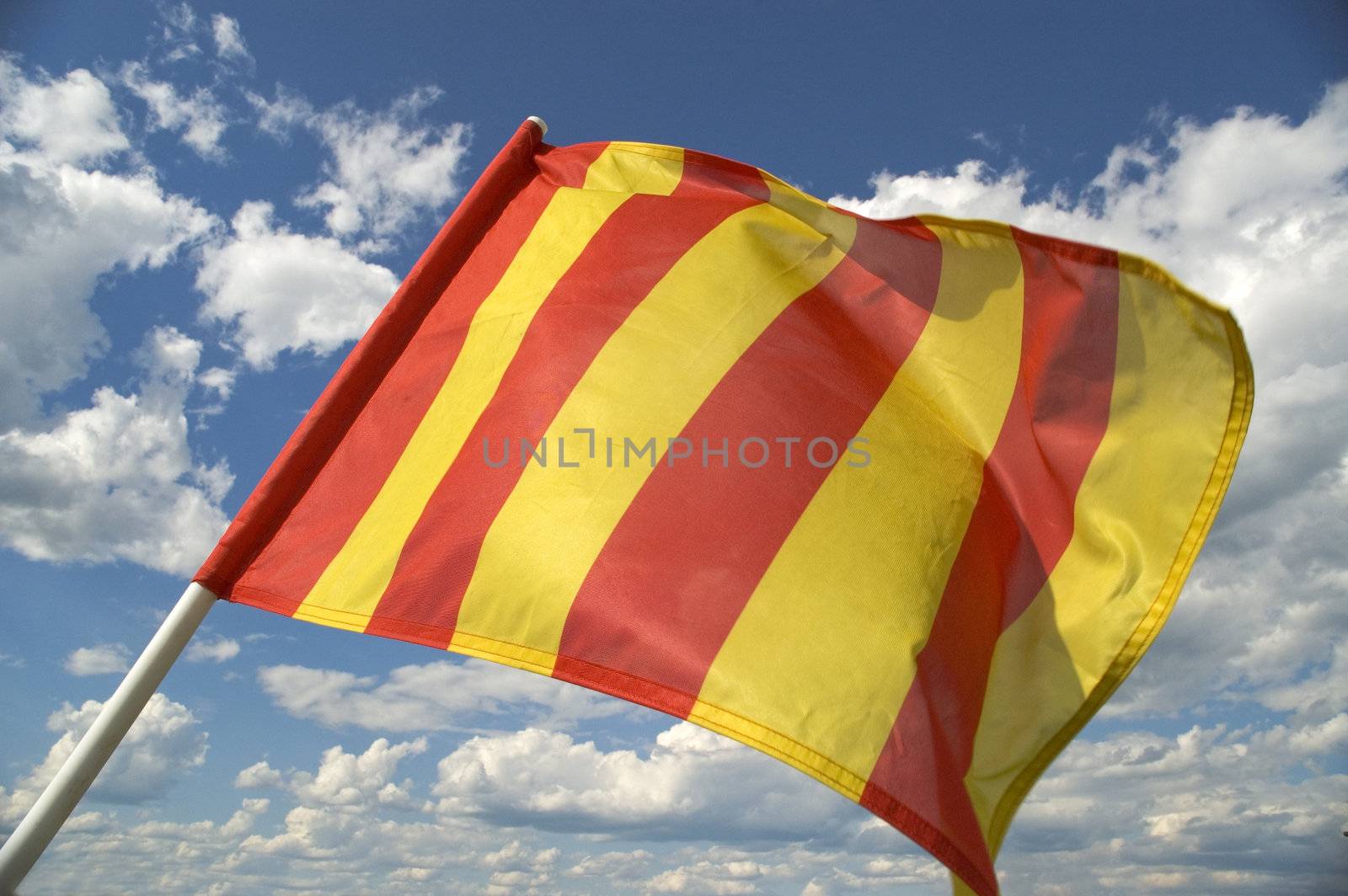The orange striped flag on a background of the dark blue sky with clouds is yellow.