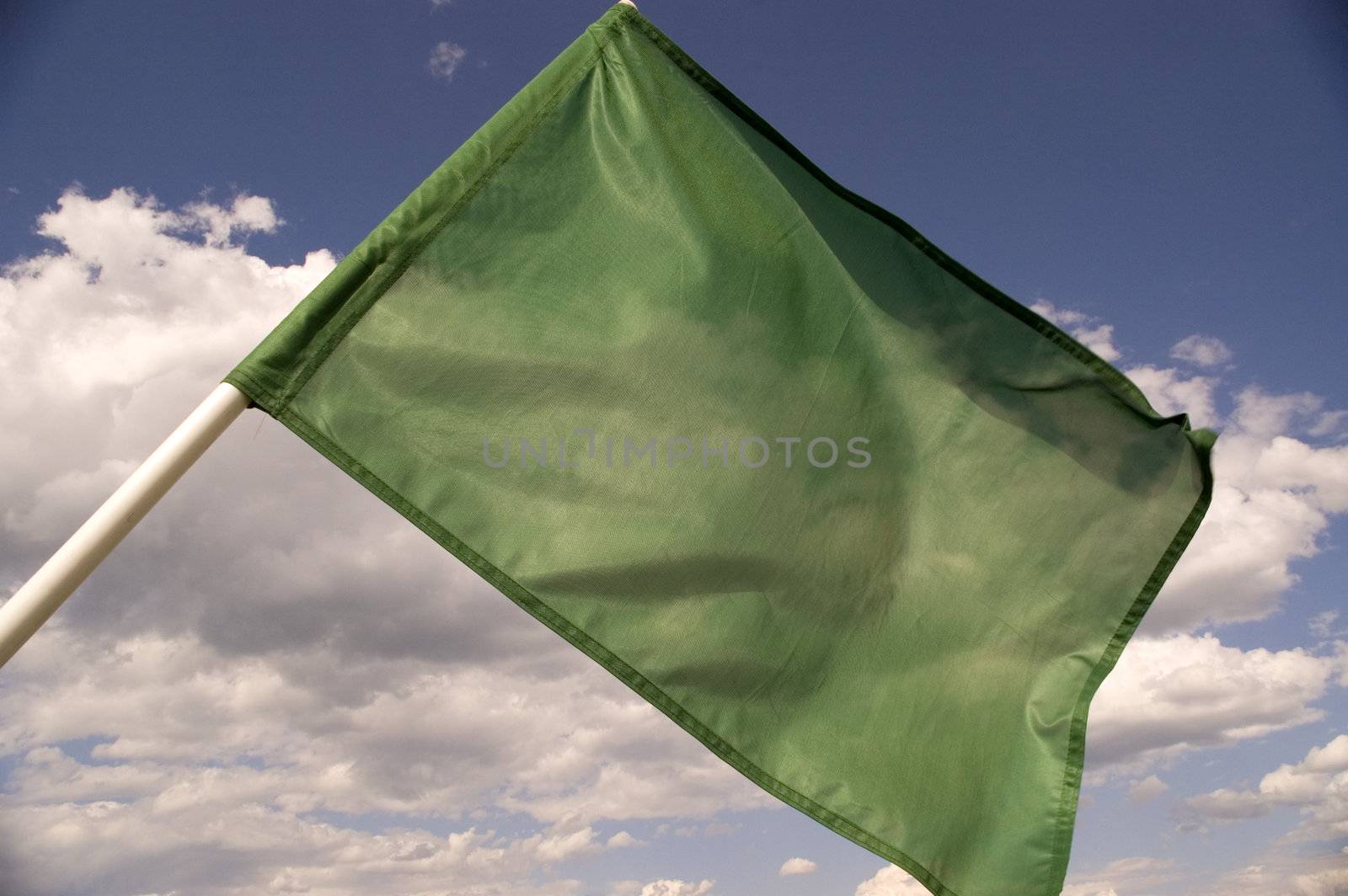 Green flag on a background of the dark blue sky with clouds.