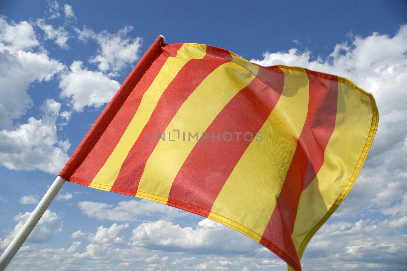 The orange striped flag on a background of the dark blue sky with clouds is yellow .