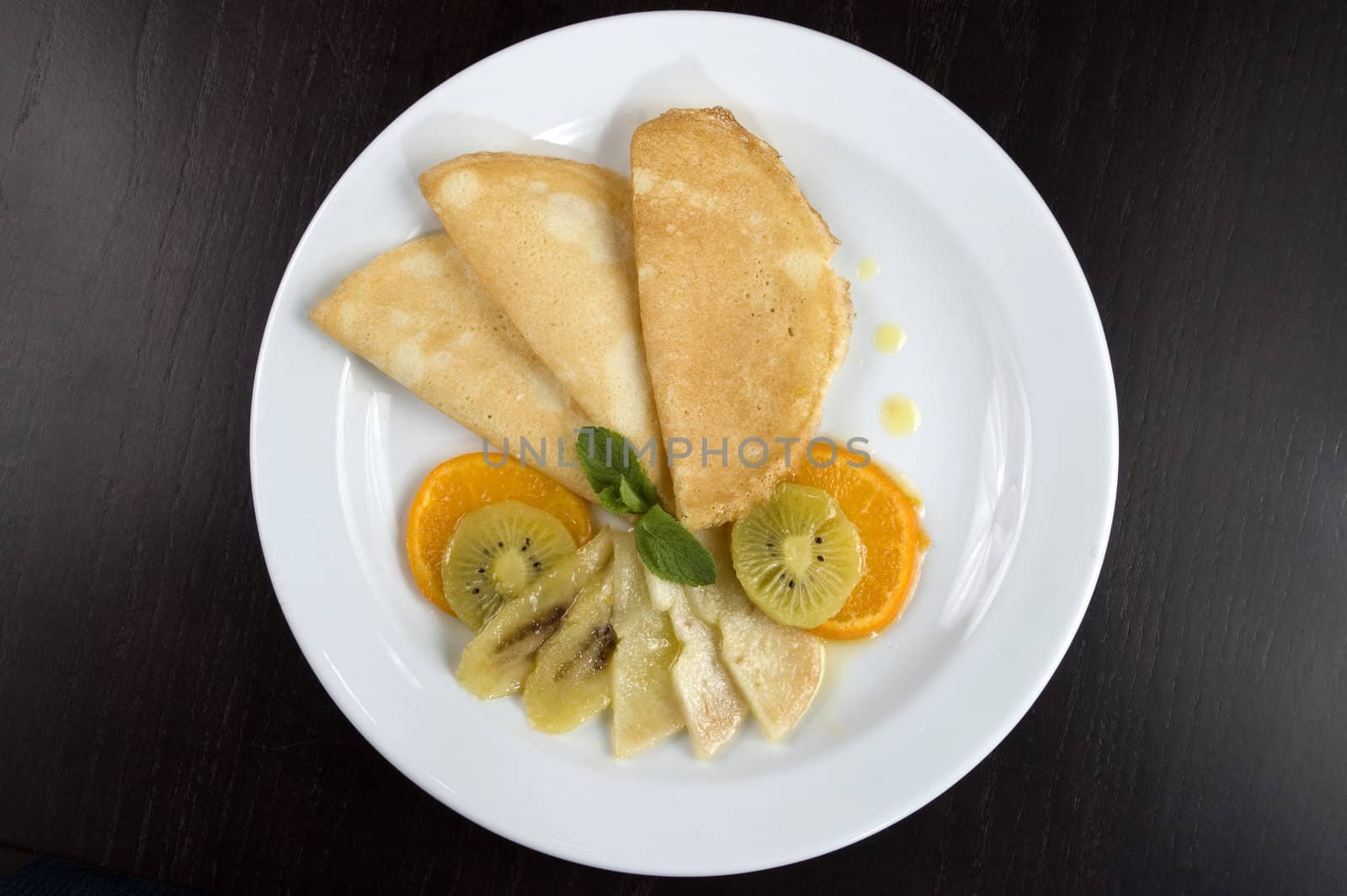 Pancakes with fruit on a white plate.