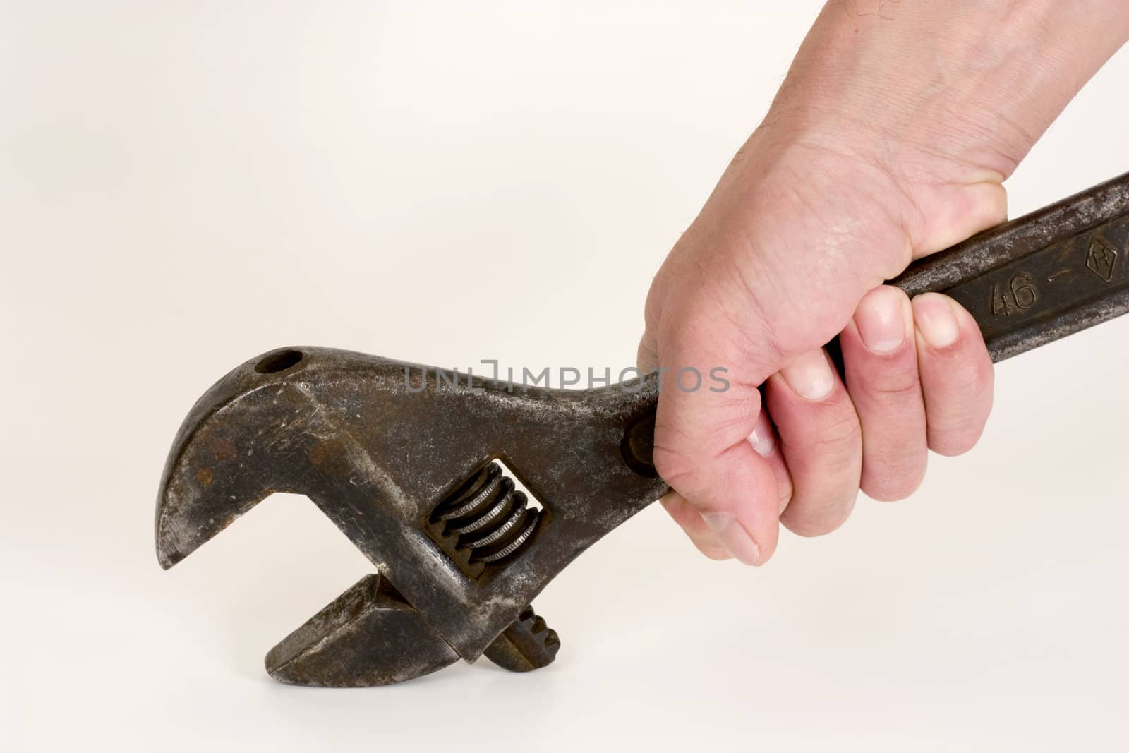 Old spanner in a hand on a light background.