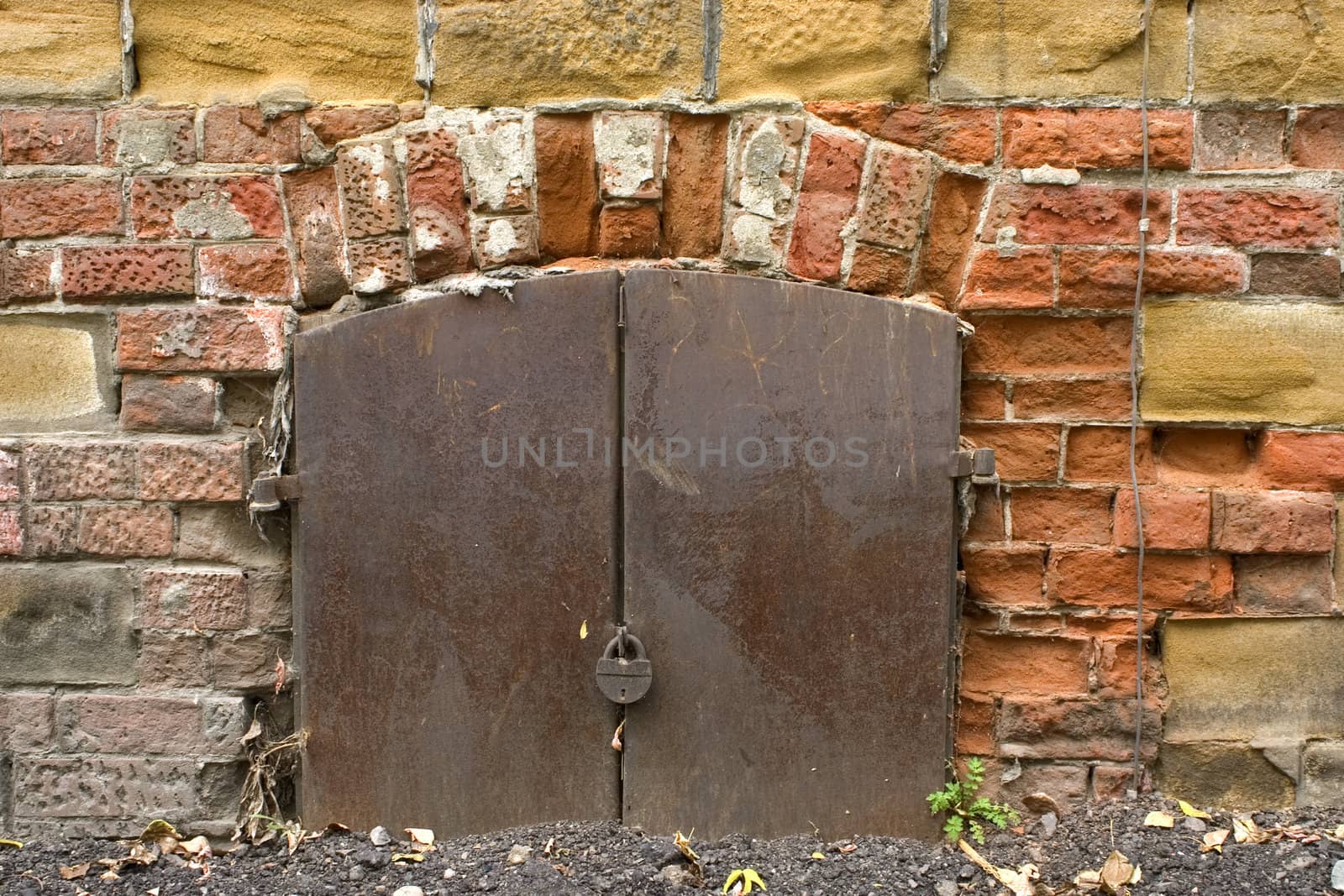 Old brick wall, metal door with the lock.