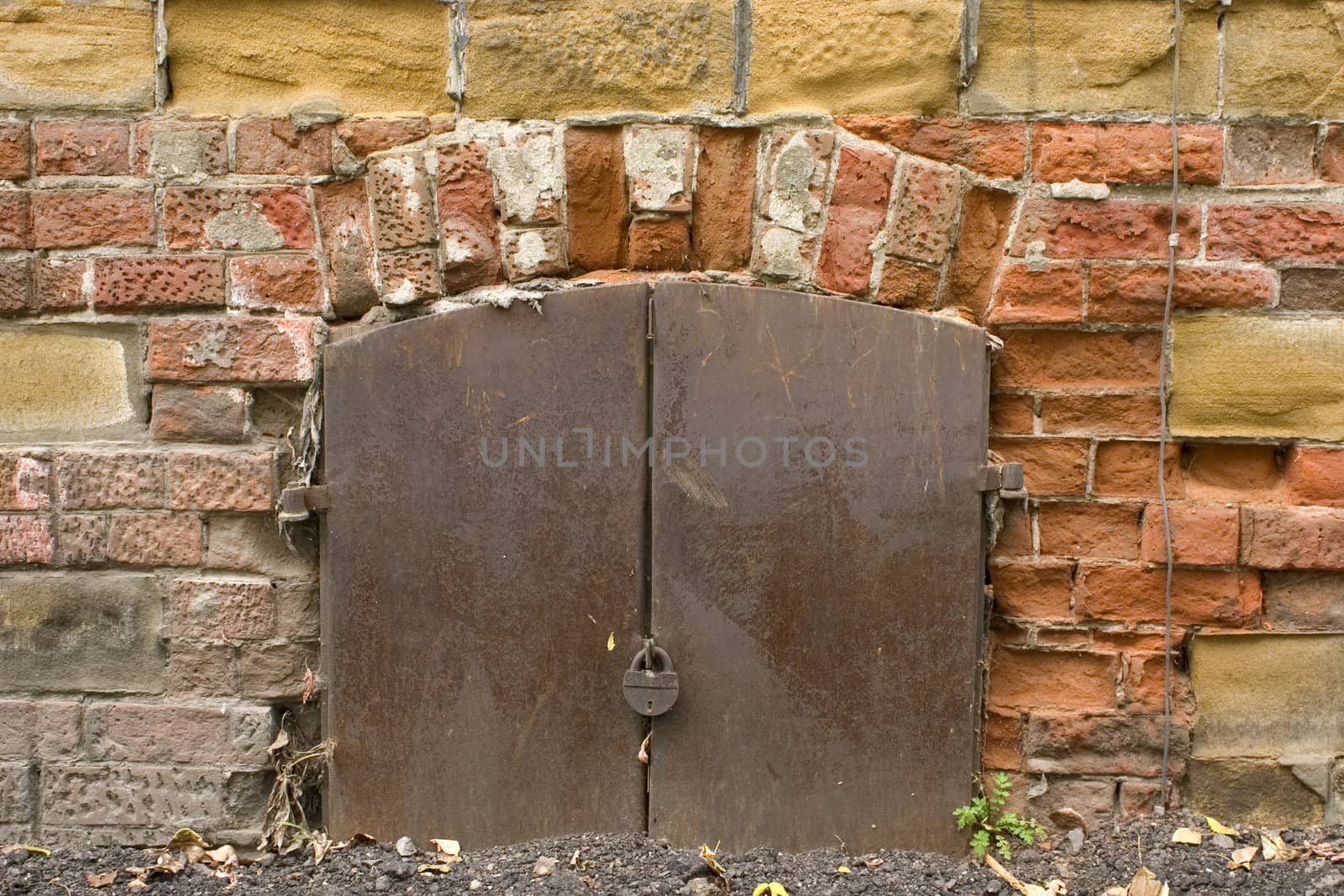 Old brick wall, metal door with the lock.