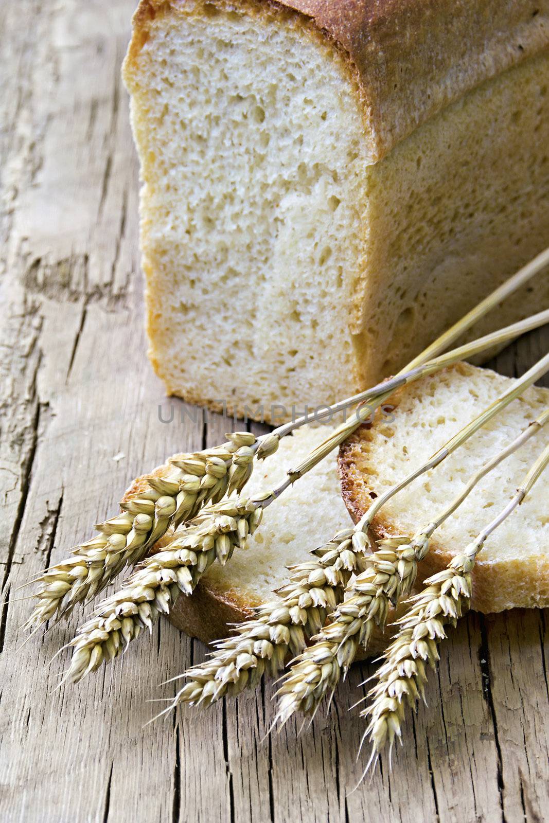 a loaf of bread and wheat ears in the background