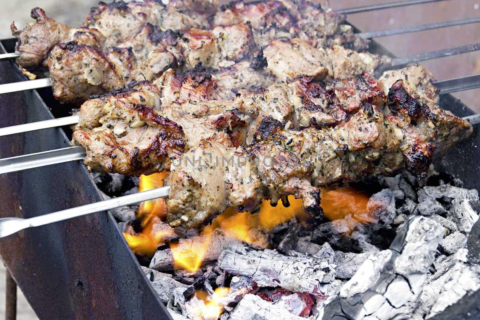 image pieces of meat roasted on a spit over charcoal