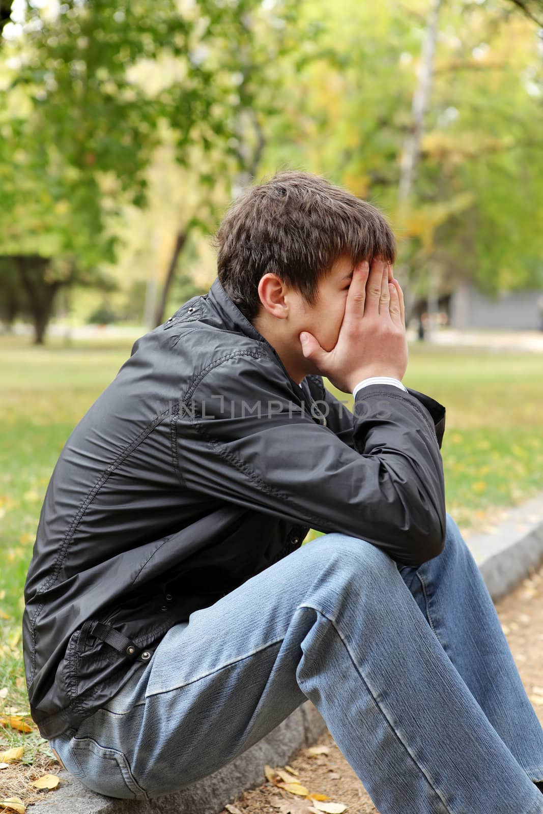 sad young man sitting in the autumn park