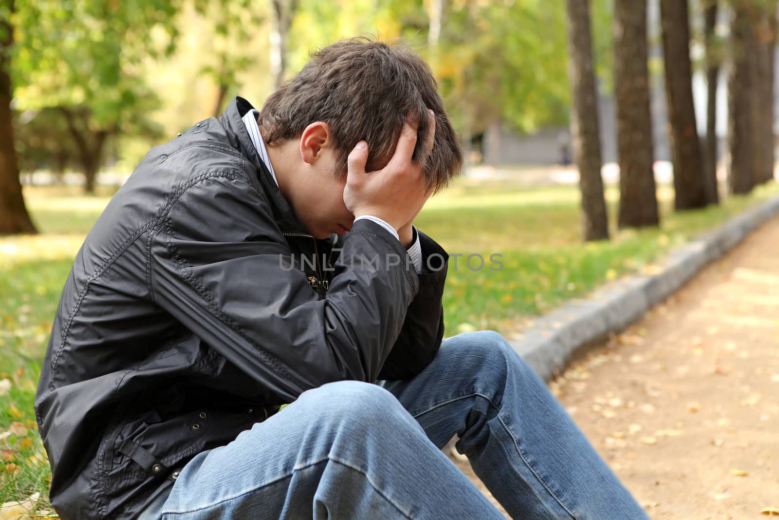 sad young man sitting in the autumn park