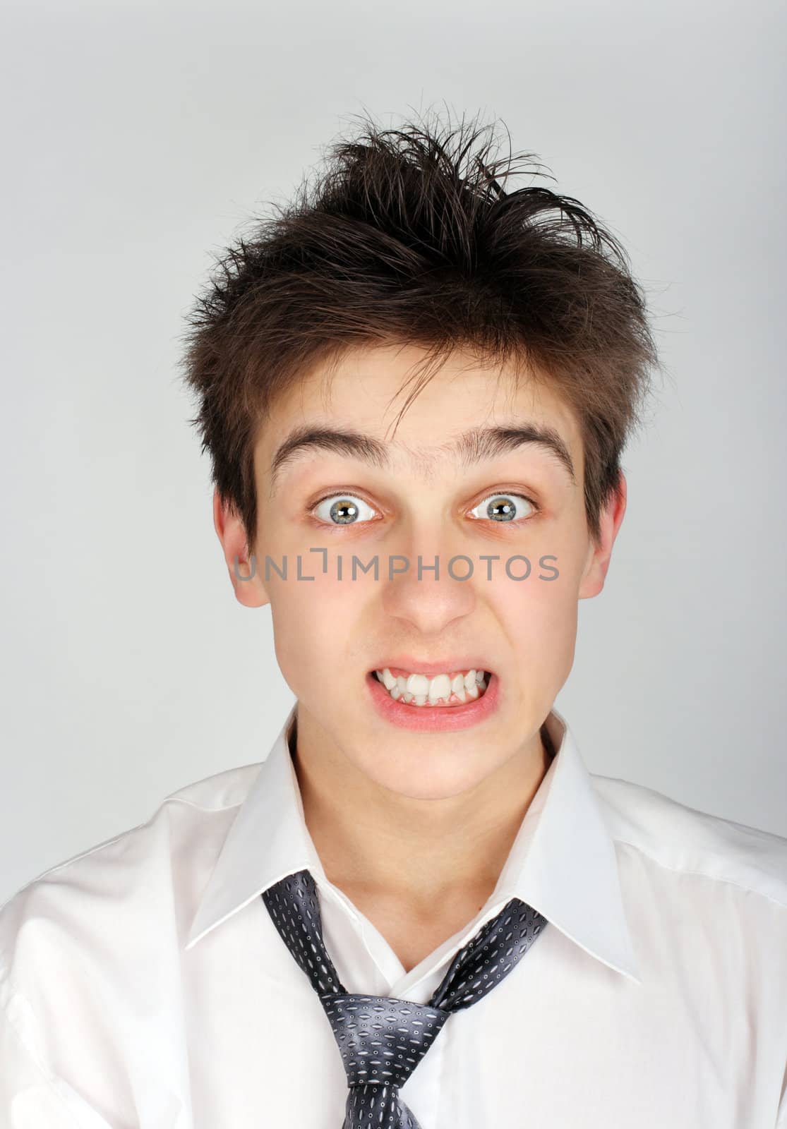 Portrait of Angry and Shaggy Teenager on the Gray Background