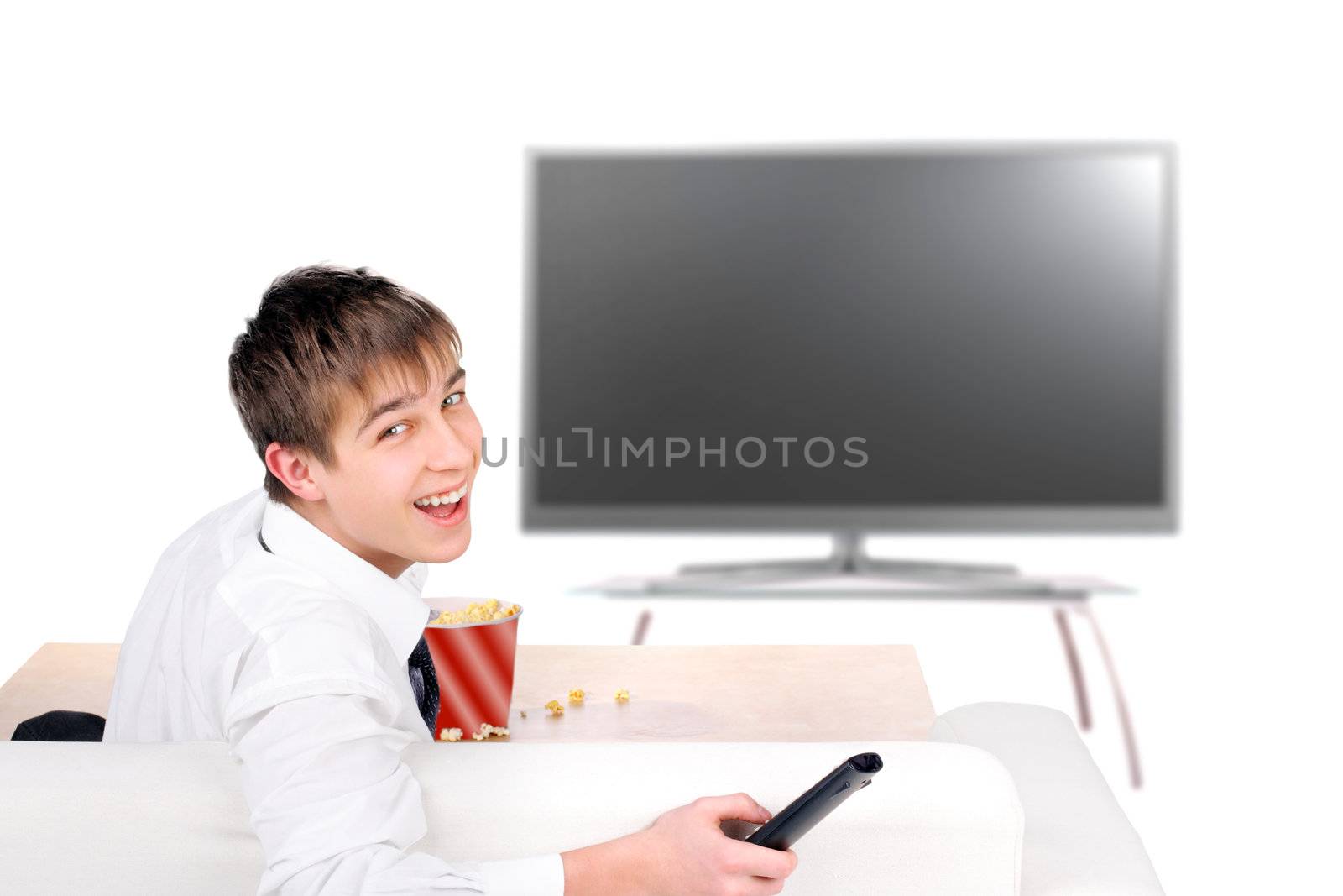 Happy Teenager with Remote control sitting on the Sofa and Watching Tv