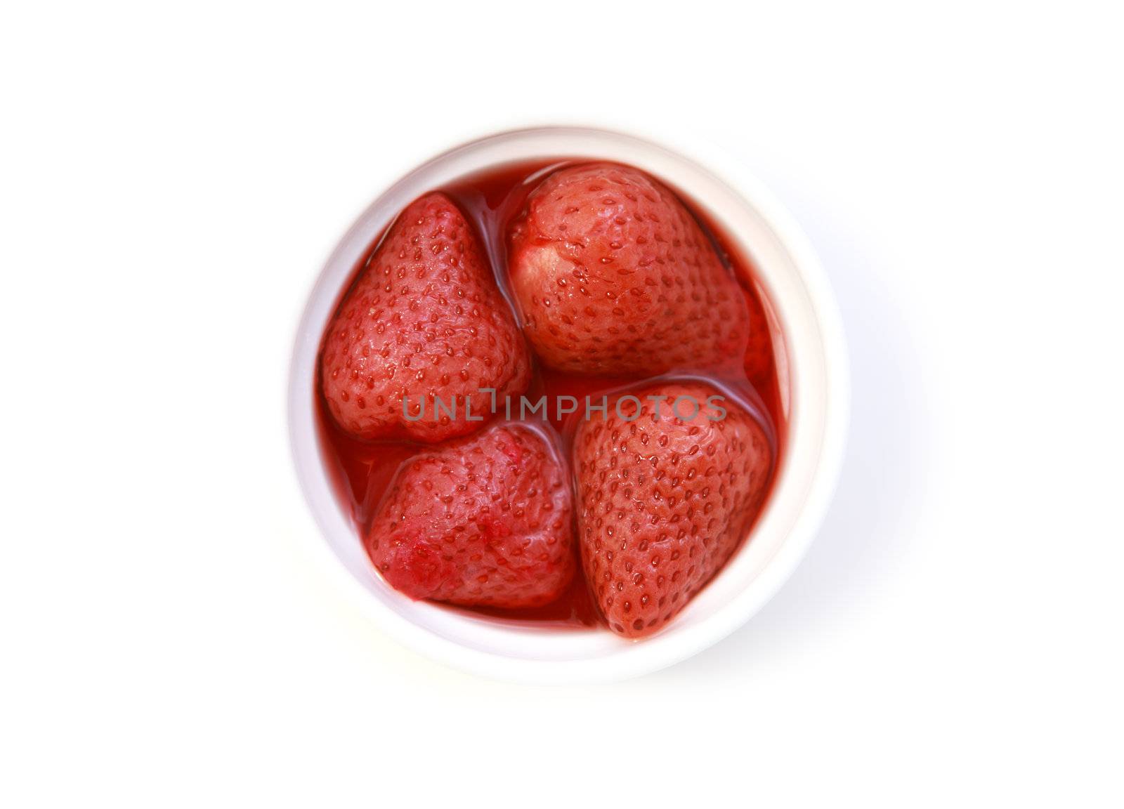 four strawberries in their own juice on the plate on white background