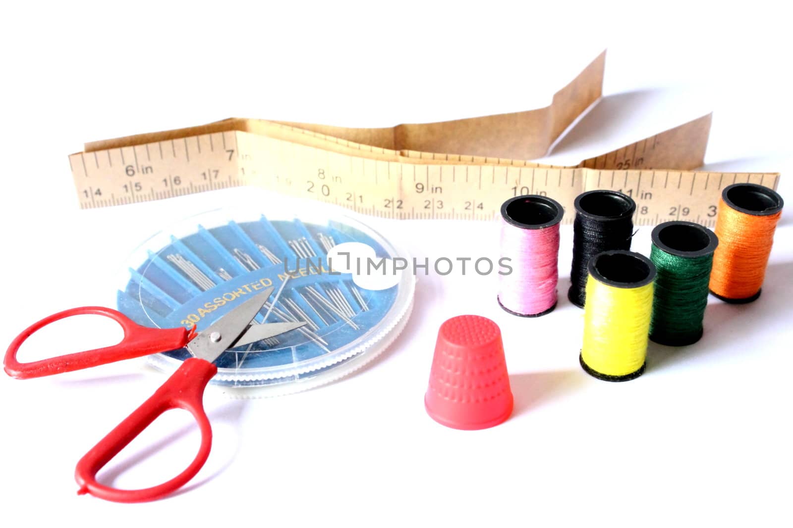 Isolated sewing kit with scissors, thimble, thread, needles, and tape measure.