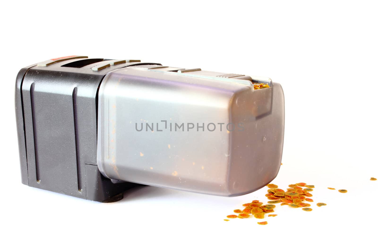 Isolated automatic fish feeder with fish food on the ground.