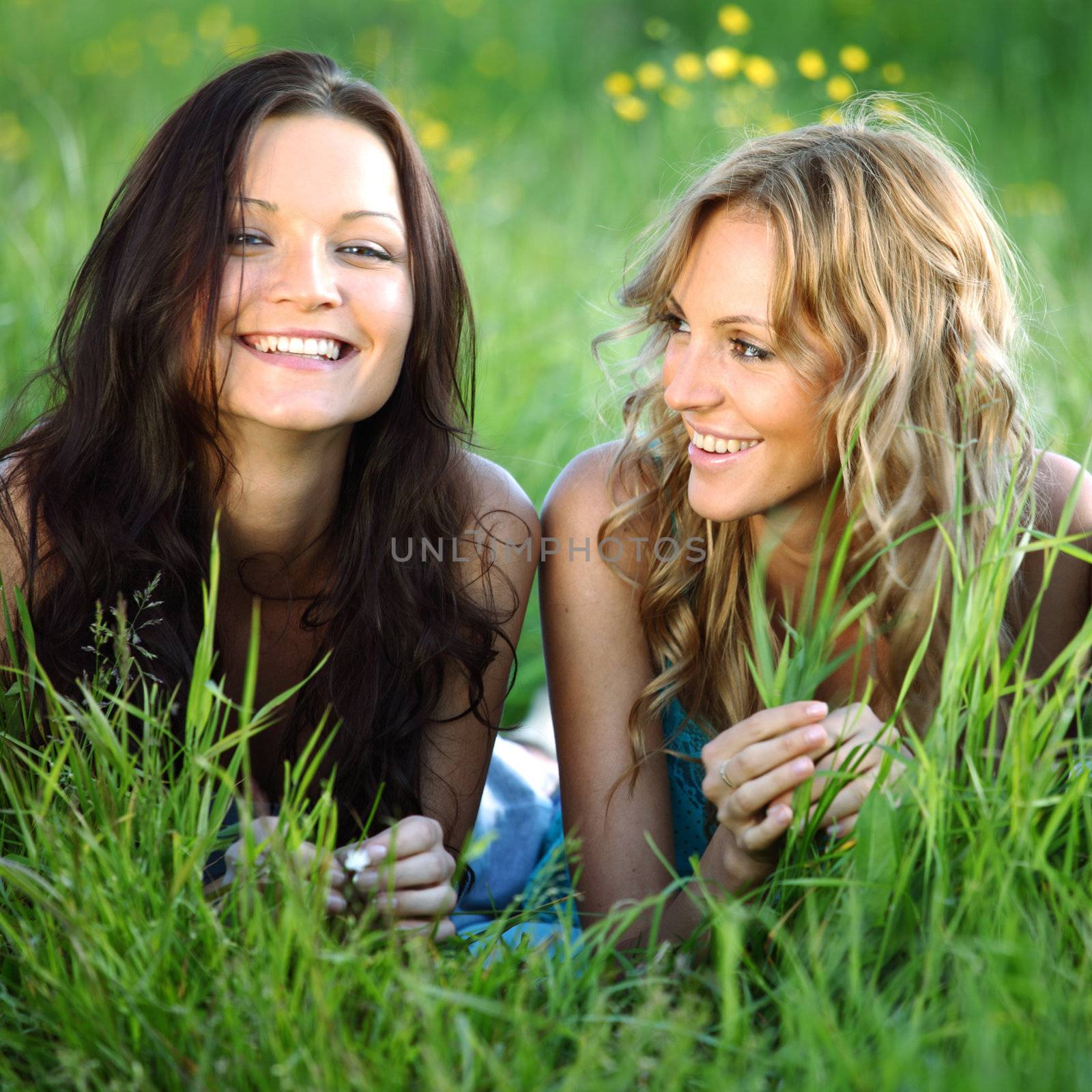 girlfriends lays on green grass and smile