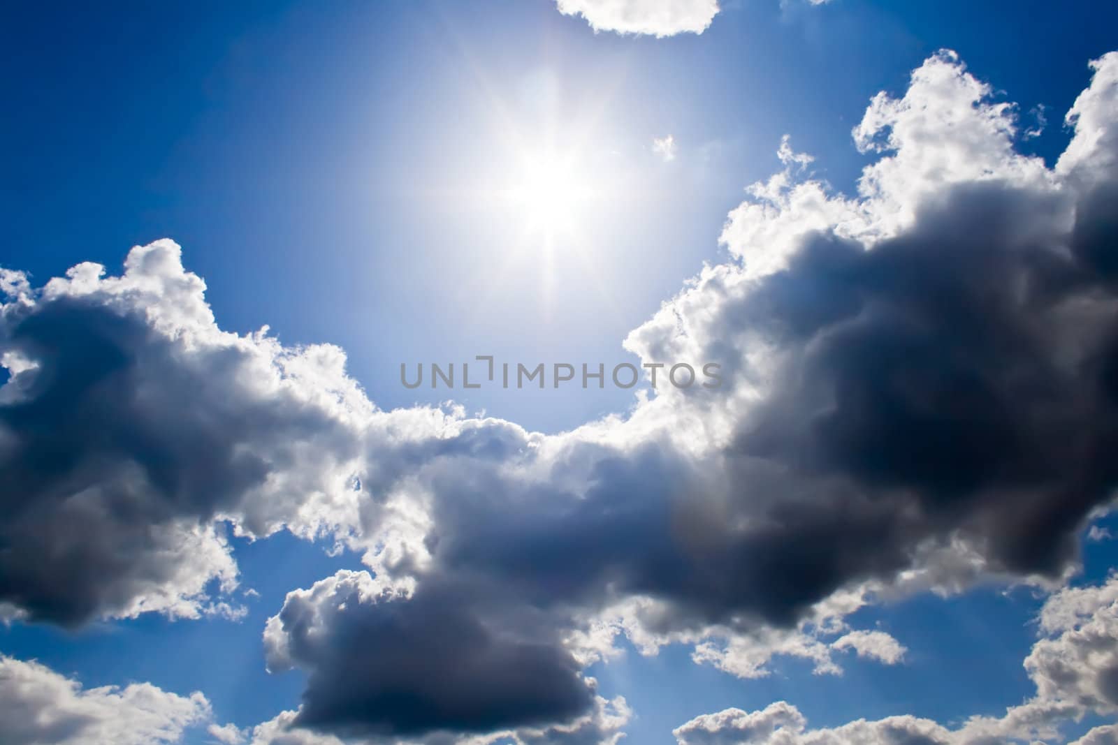 Bright sunrays in a blue cloudy sky