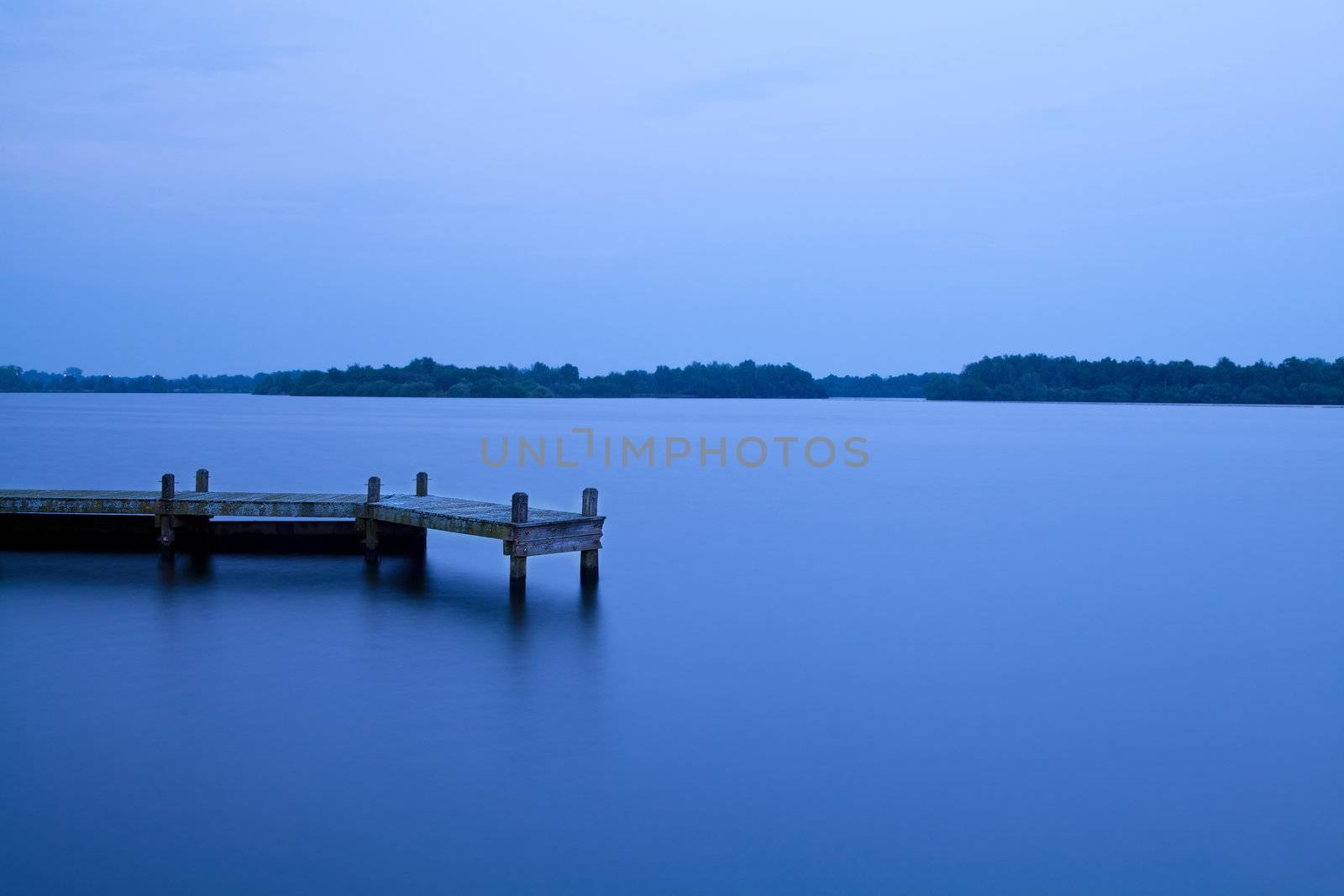 wooden pier on the lake at dusk after sunset