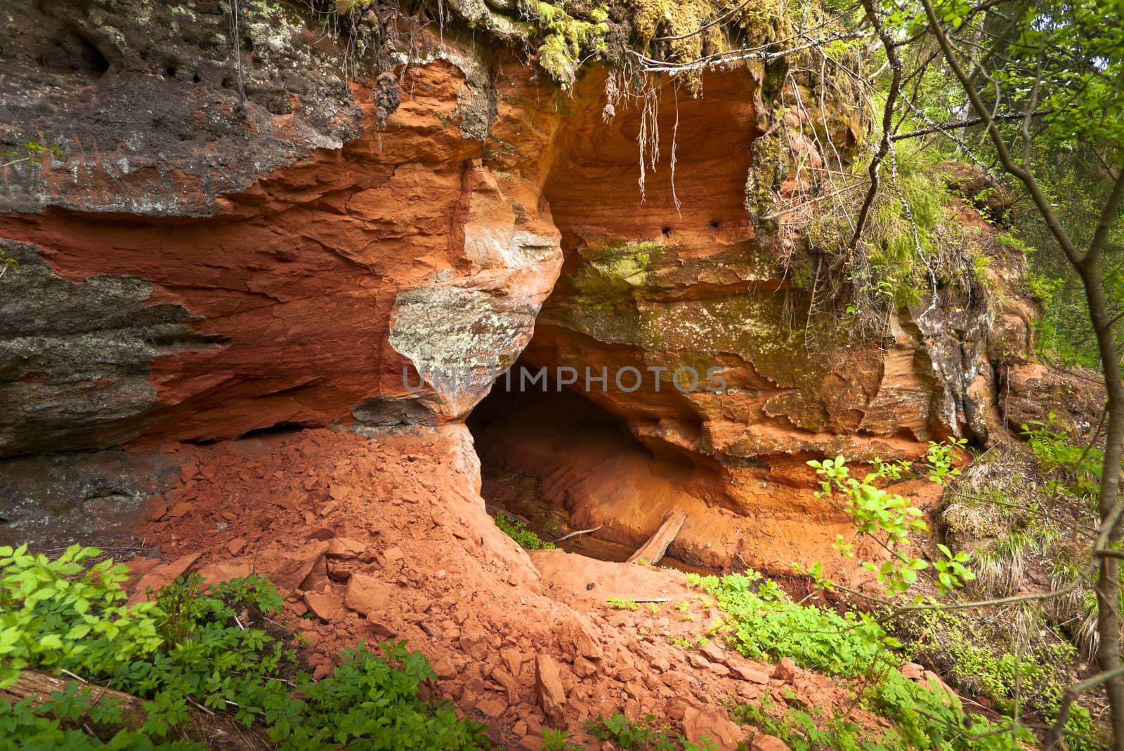 Red cave with falling pressed sand at the entrance