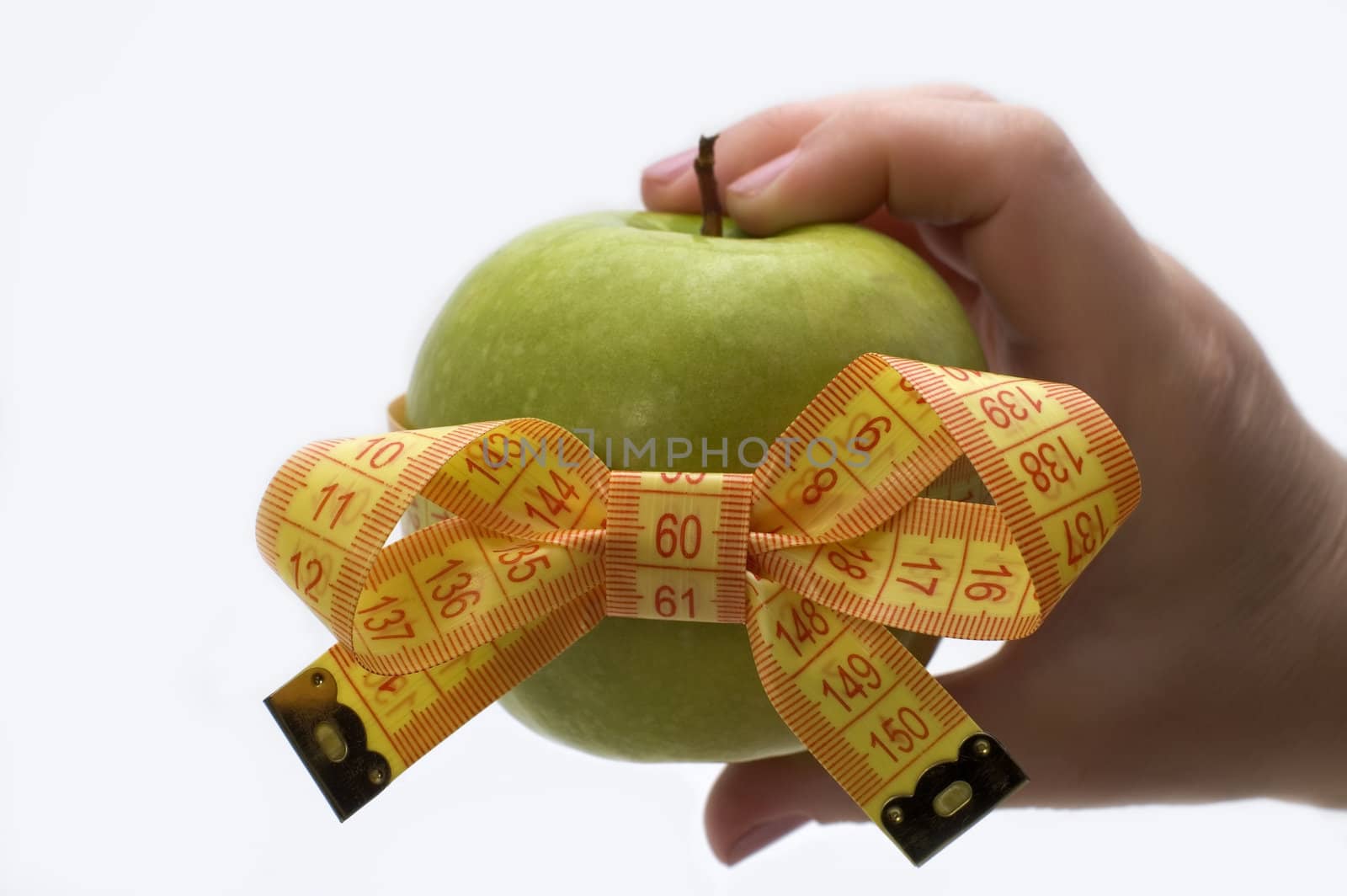 Green apple with measuring tape in a hand.
