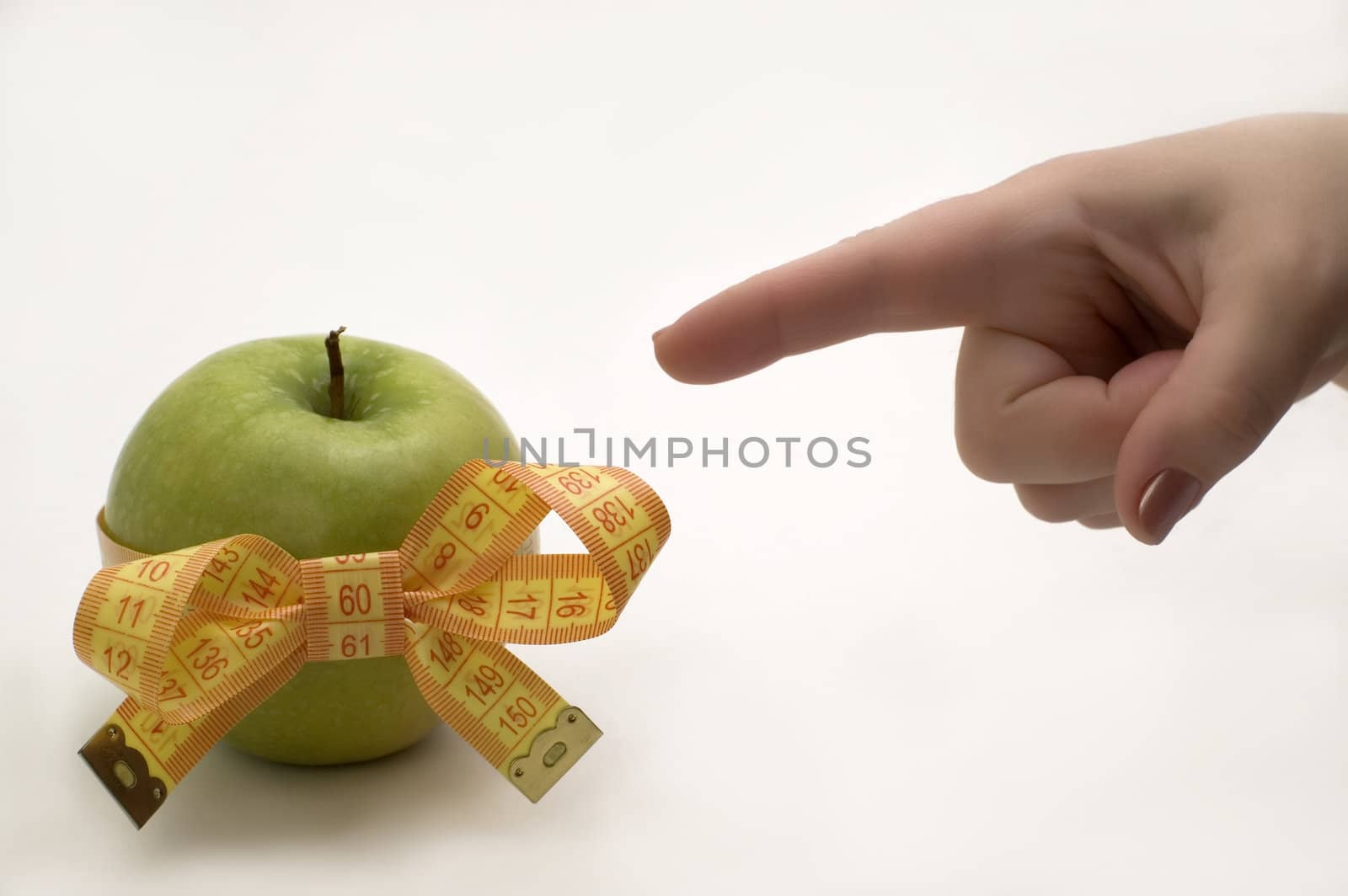 Green apple with measuring tape in a hand.