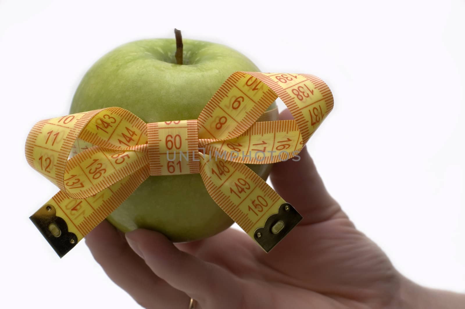 Green apple with measuring tape in a hand.