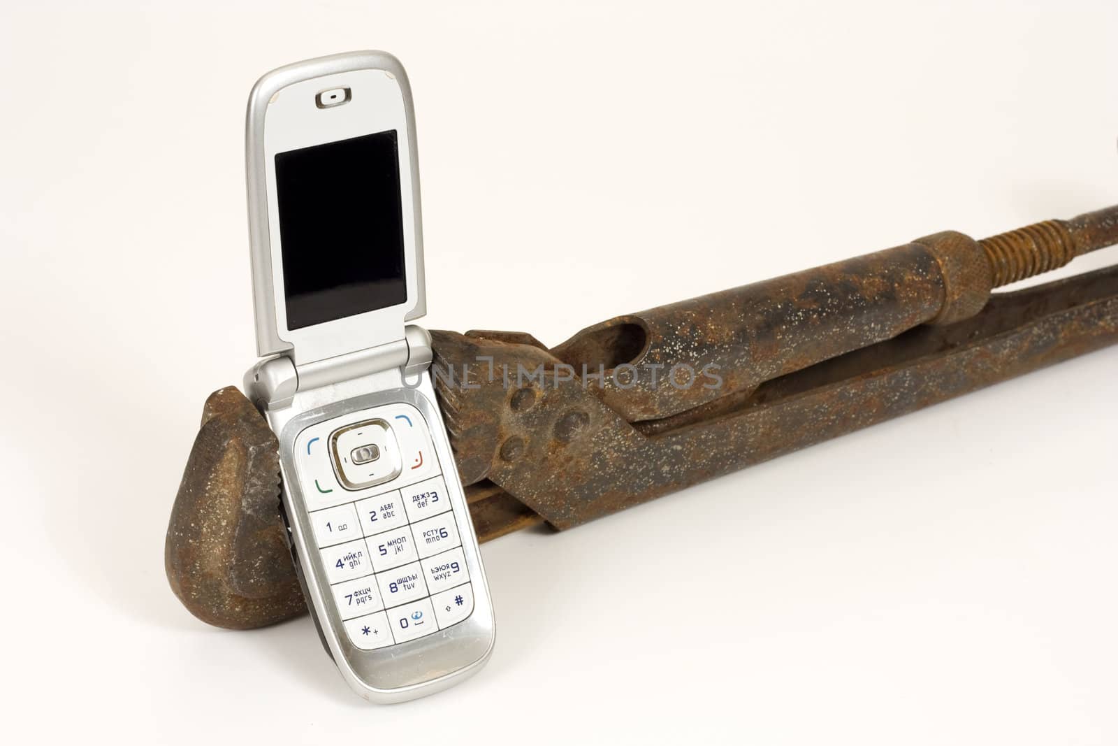 Old rusty spanner and modern telephone.