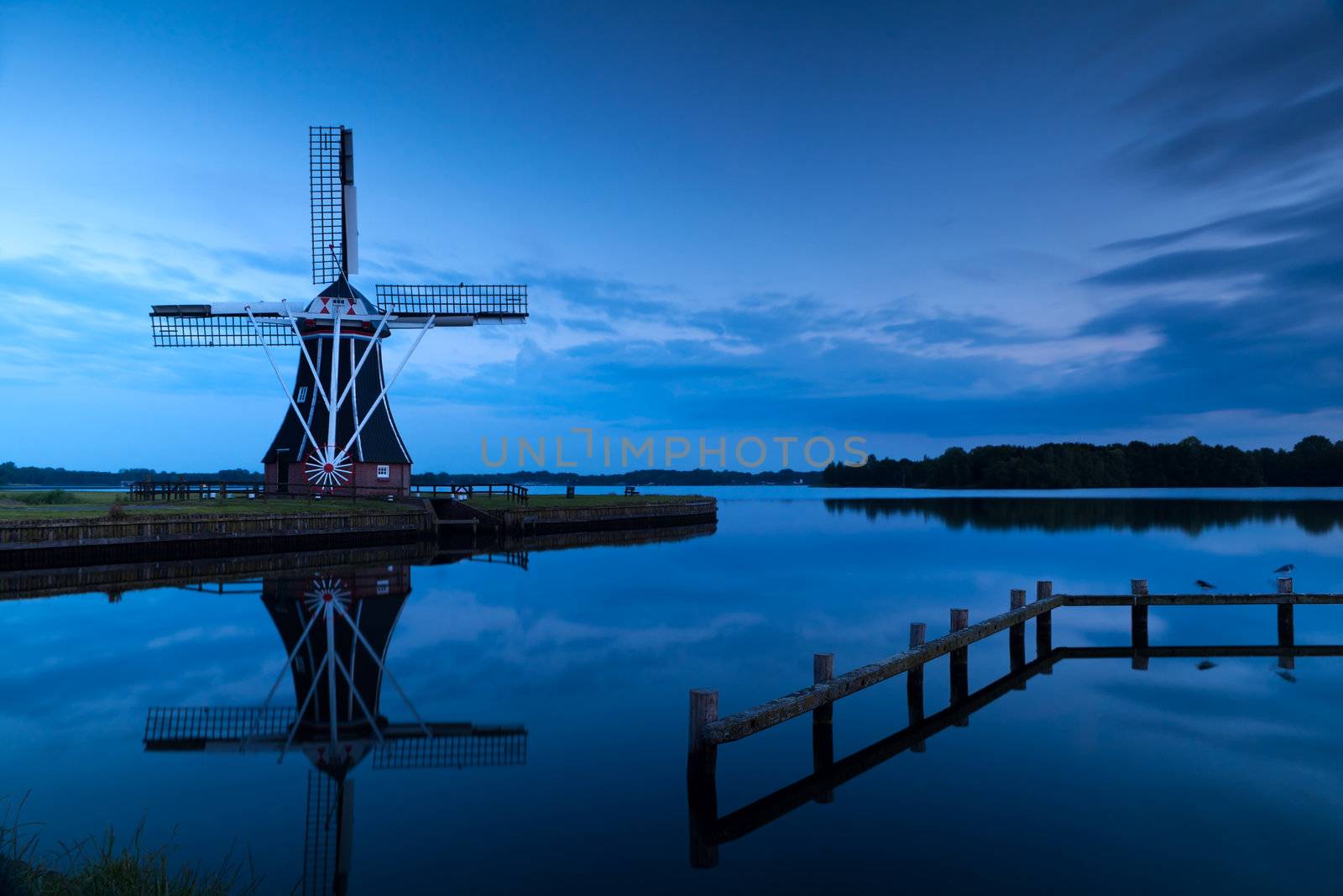 windmill close to lake at sunset