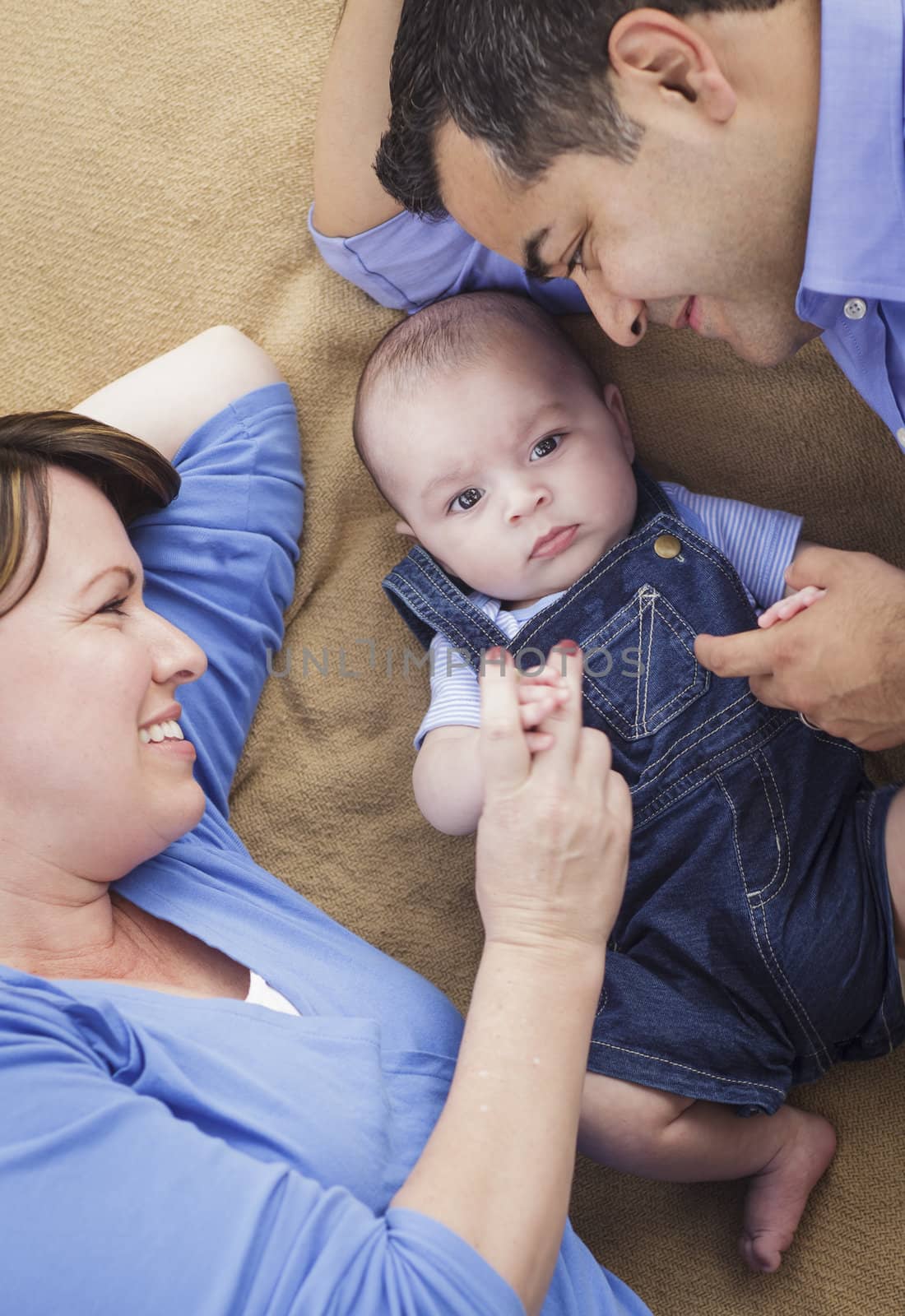 Mixed Race Family with Baby Boy Playing Face Up on the Blanket.