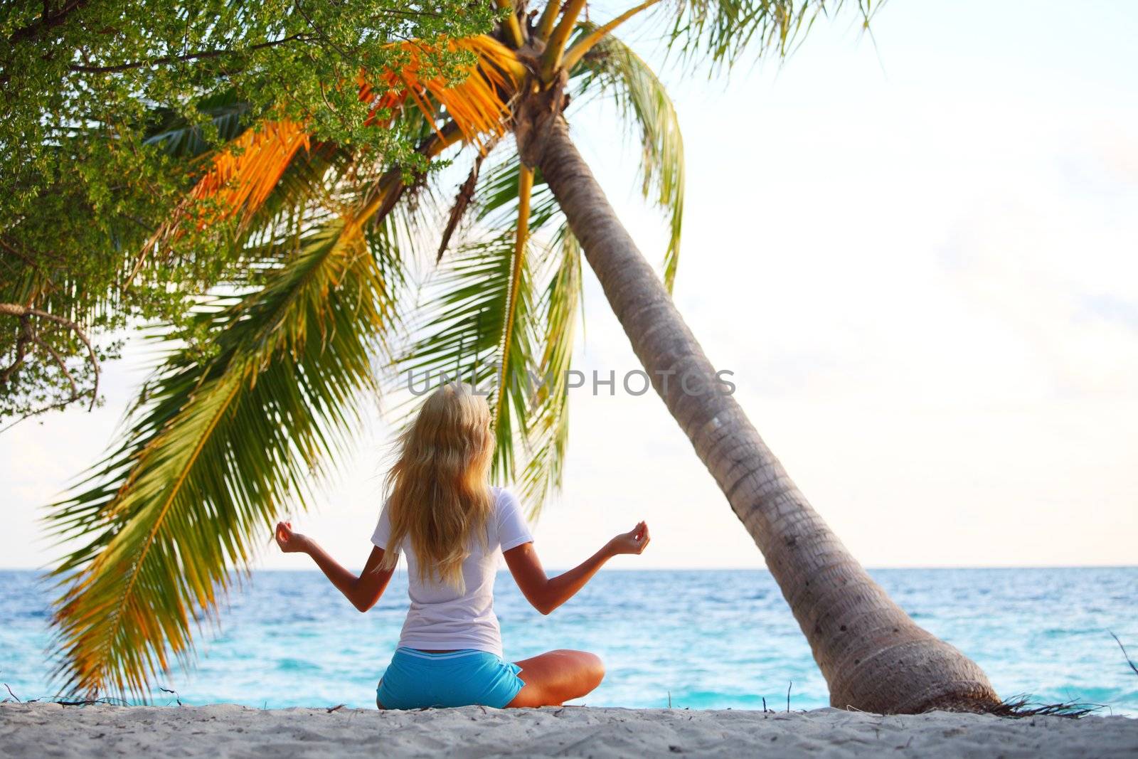 yoga woman on sea coast under palm