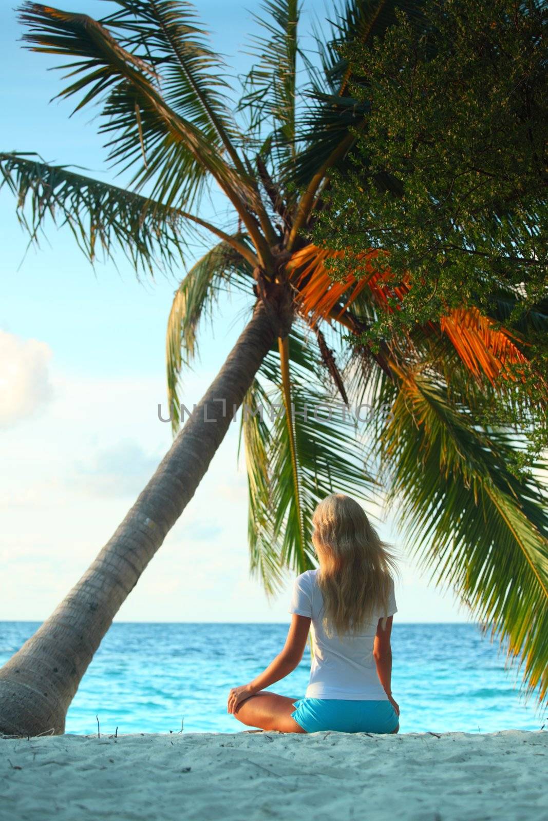 yoga woman on sea coast under palm