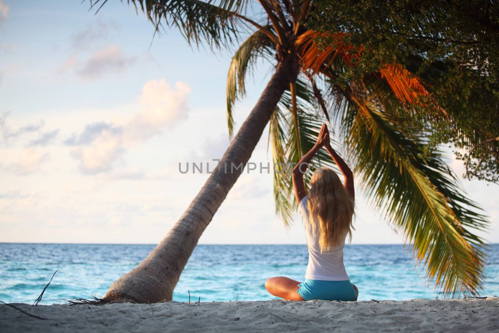 yoga woman on sea coast under palm