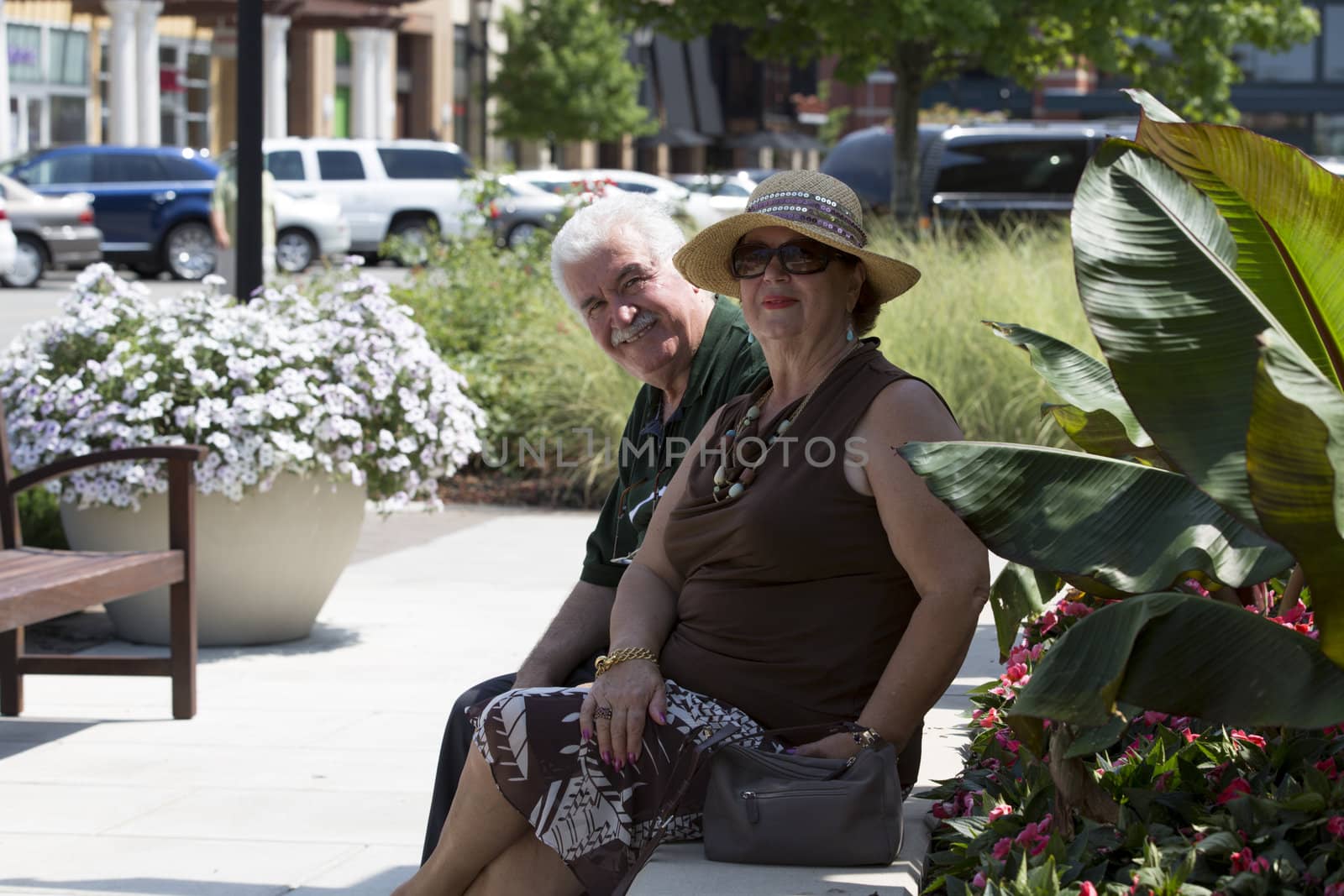 Older husband and wife enjoying their time out under the sun. She is wearing her wicker hat.