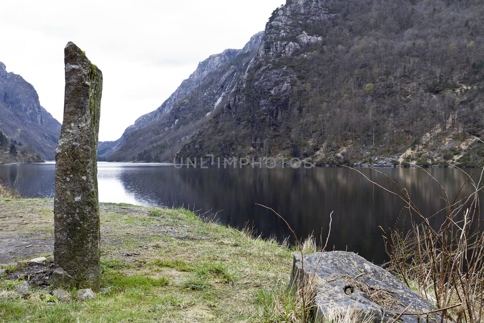 standing stone at coastline in norway with mountains in background