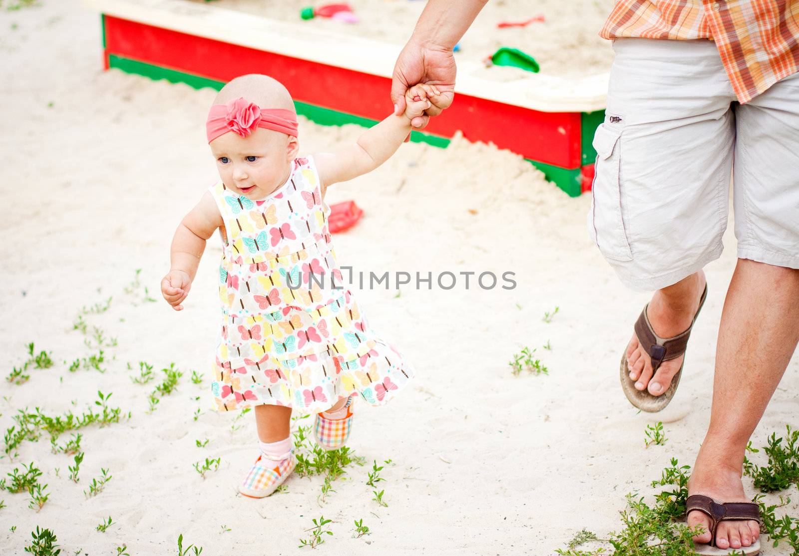 baby girl first steps holding her father hand