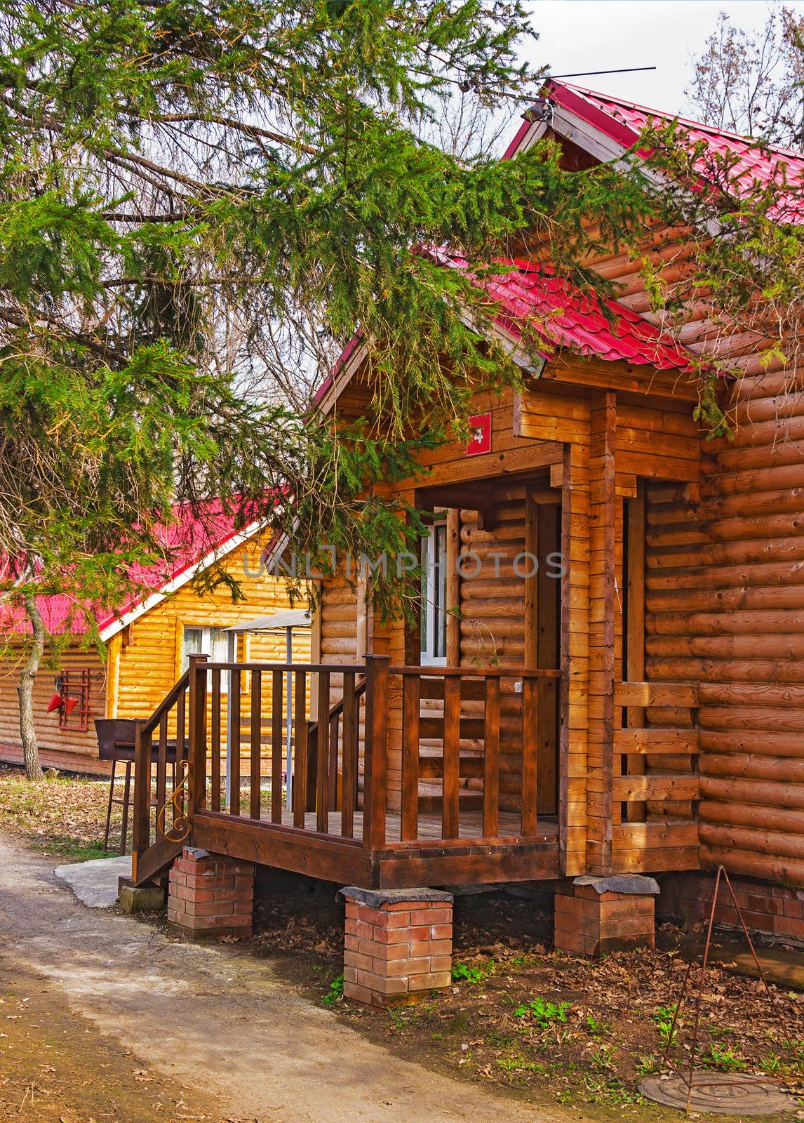 porch of a wooden cottage with a red roof in the countryside